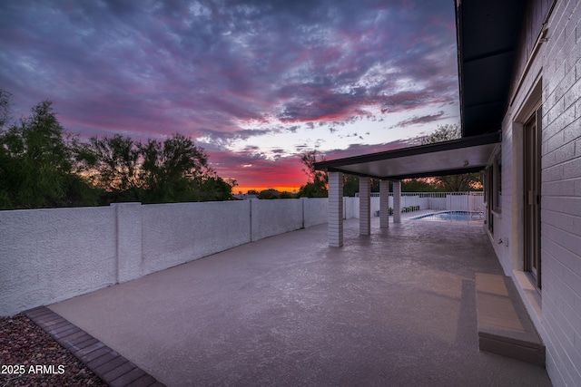 patio terrace at dusk with a fenced in pool