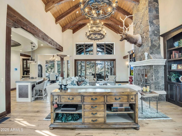 interior space with wooden ceiling, light hardwood / wood-style flooring, high vaulted ceiling, beamed ceiling, and a fireplace