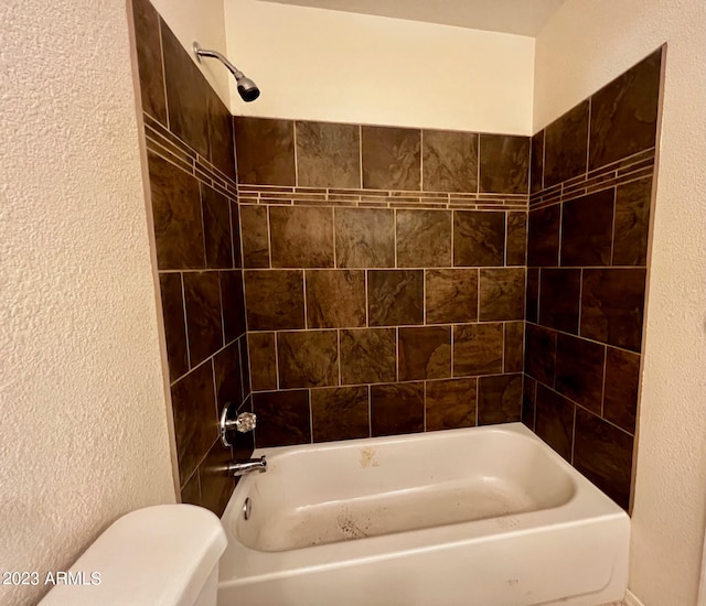 bathroom with tiled shower / bath combo and toilet