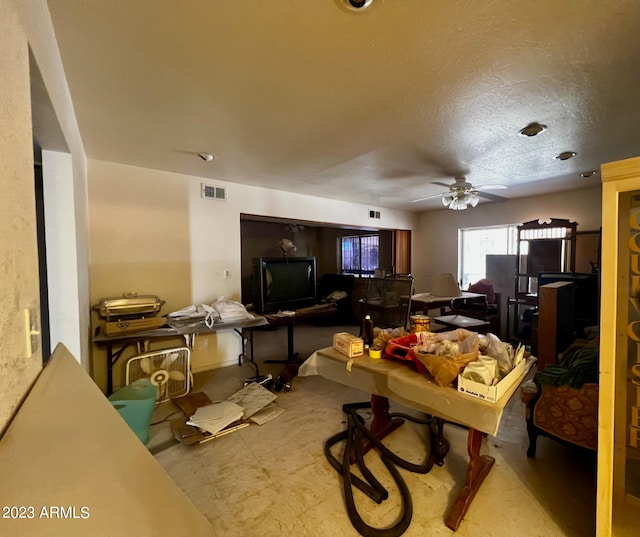 living room with a textured ceiling and ceiling fan