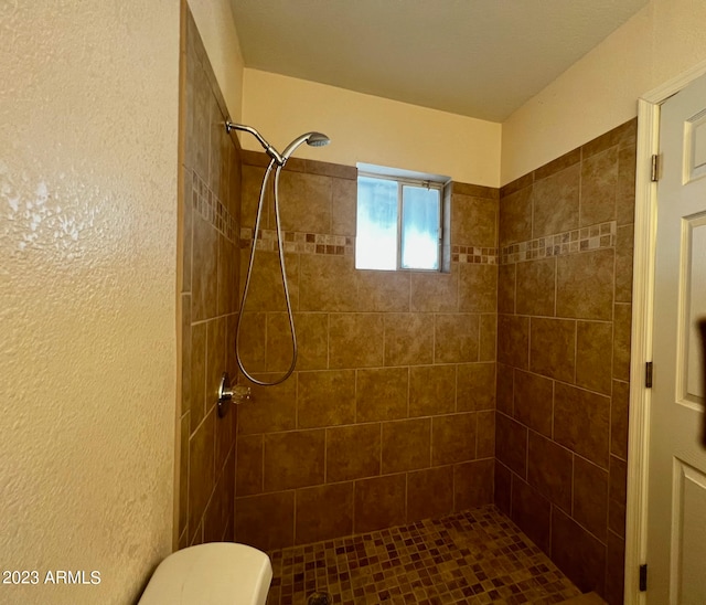 bathroom with toilet and a tile shower