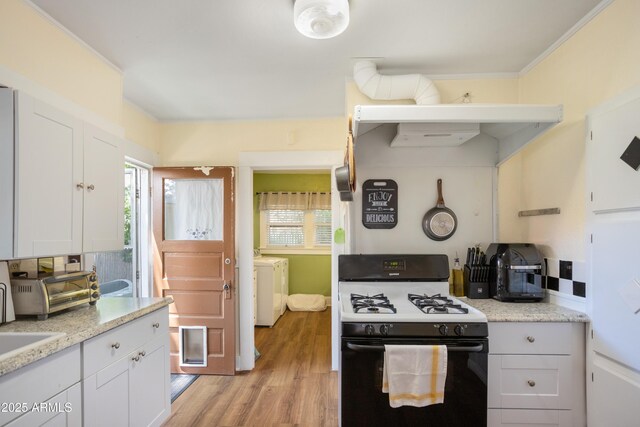 24 Black Knob Vw, Bisbee, AZ 85603 - kitchen with gas stove, washing machine and clothes dryer, light wood-style floors, white cabinetry, and ornamental molding