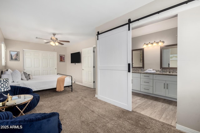 508 S Ernie Pl, Tempe, AZ 85281 - bedroom with light carpet, baseboards, a barn door, connected bathroom, and a sink