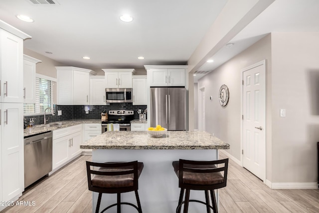 508 S Ernie Pl, Tempe, AZ 85281 - kitchen with a breakfast bar area, a center island, a sink, light wood finished floors, and stainless steel appliances