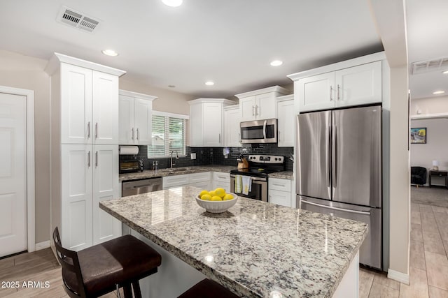 508 S Ernie Pl, Tempe, AZ 85281 - kitchen with a breakfast bar area, visible vents, appliances with stainless steel finishes, a sink, and white cabinetry