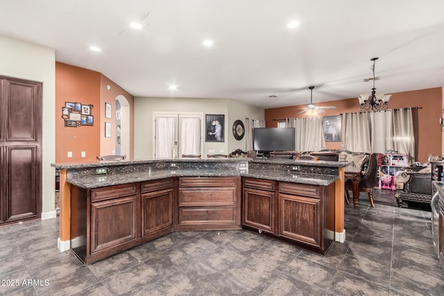 kitchen featuring recessed lighting, dark stone counters, arched walkways, and open floor plan