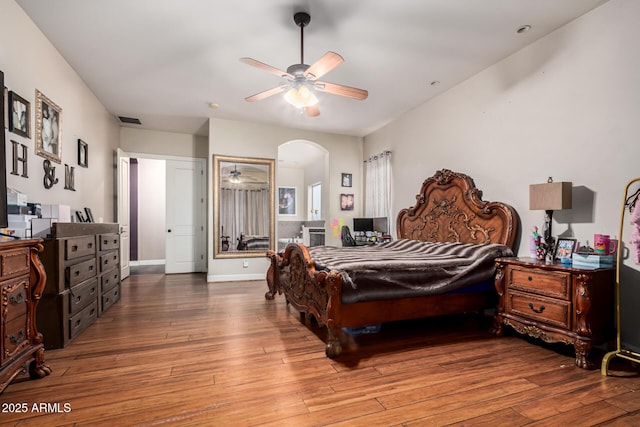 bedroom featuring visible vents, arched walkways, wood-type flooring, and baseboards