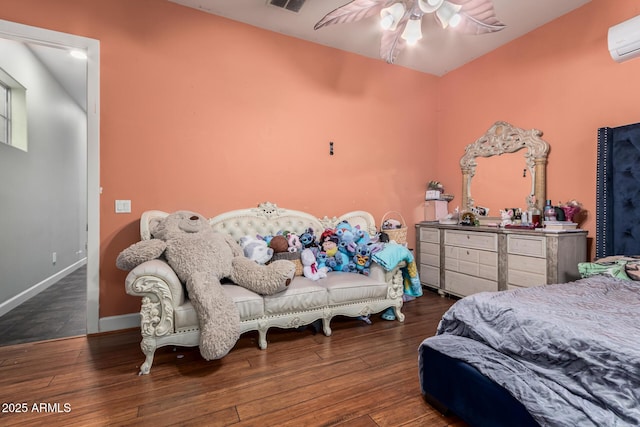 bedroom with visible vents, baseboards, wood finished floors, and a wall unit AC