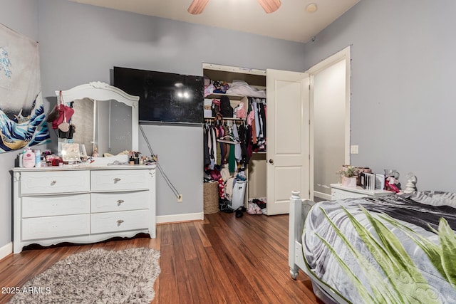 bedroom with a spacious closet, ceiling fan, baseboards, a closet, and dark wood-style flooring