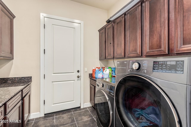 laundry area featuring washing machine and clothes dryer, cabinet space, baseboards, and dark tile patterned flooring