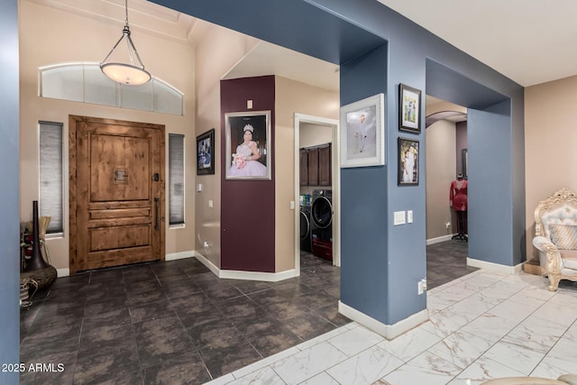 foyer featuring baseboards, arched walkways, separate washer and dryer, and marble finish floor