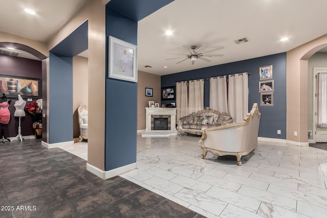 living room with arched walkways, marble finish floor, baseboards, and a ceiling fan