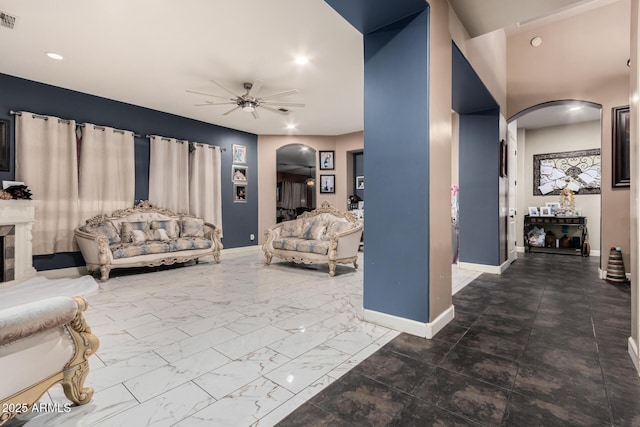 living area with a ceiling fan, visible vents, baseboards, arched walkways, and marble finish floor