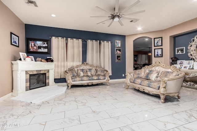 living area featuring visible vents, arched walkways, marble finish floor, and a ceiling fan