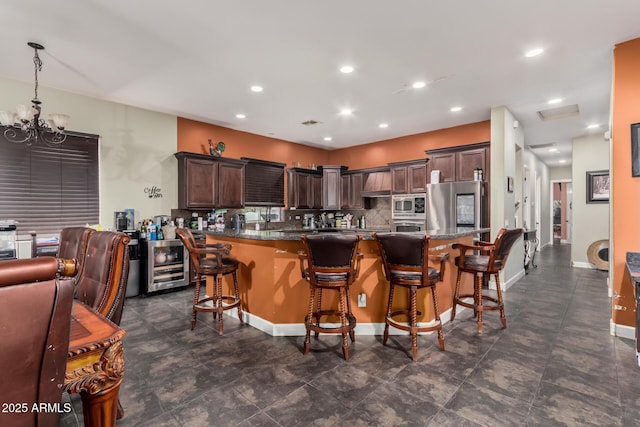 kitchen with a breakfast bar, backsplash, stainless steel appliances, wine cooler, and dark brown cabinetry