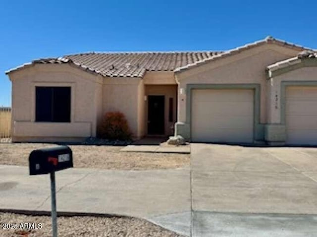 view of front of property with a garage, concrete driveway, a tiled roof, and stucco siding