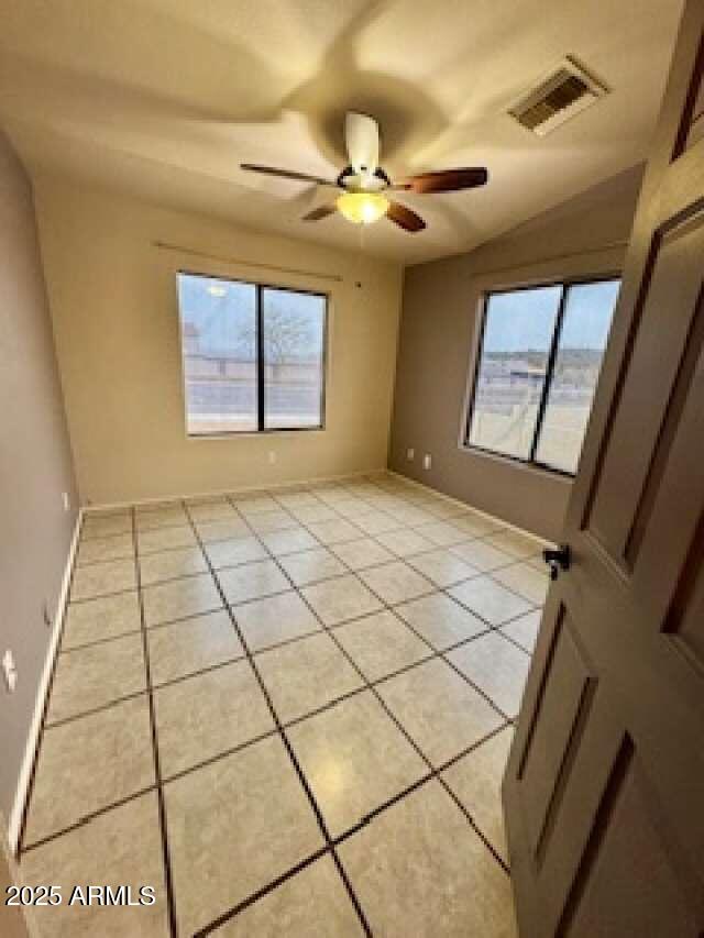 spare room with baseboards, visible vents, a ceiling fan, and light tile patterned flooring