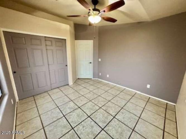 unfurnished bedroom with a closet, light tile patterned flooring, and a ceiling fan