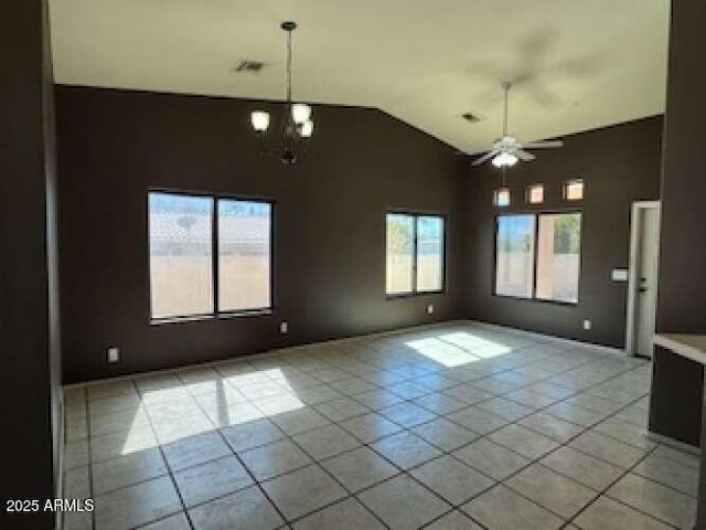 empty room with high vaulted ceiling, ceiling fan with notable chandelier, visible vents, and light tile patterned flooring