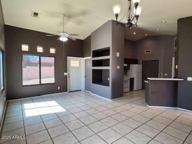 kitchen with light countertops, freestanding refrigerator, open floor plan, high vaulted ceiling, and ceiling fan with notable chandelier