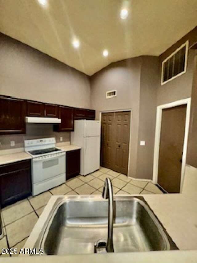 kitchen with white appliances, visible vents, light countertops, under cabinet range hood, and a sink