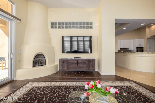 living room featuring dark hardwood / wood-style floors, a towering ceiling, and a fireplace