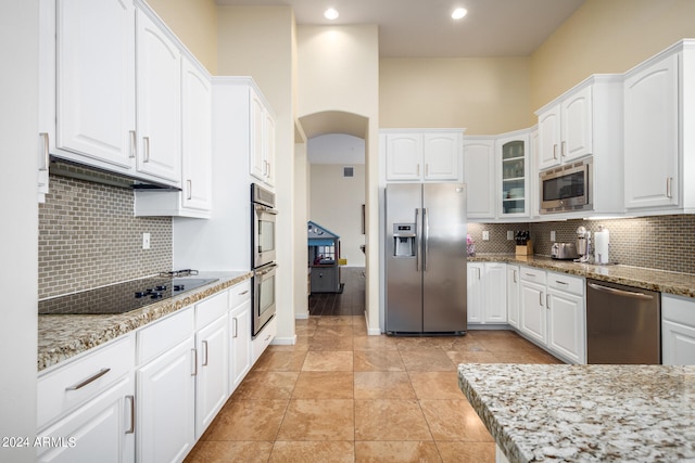 kitchen featuring light stone counters, white cabinets, and stainless steel appliances