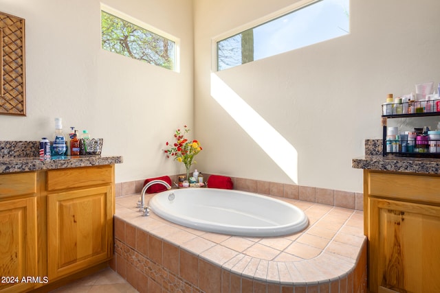 bathroom with tile patterned flooring, vanity, and tiled tub