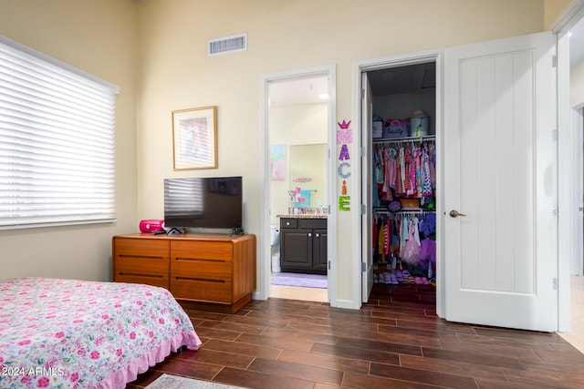 bedroom featuring ensuite bath, a spacious closet, a closet, and dark wood-type flooring