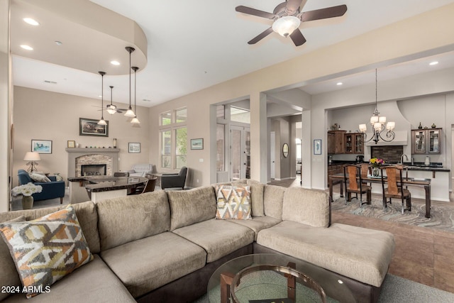 living room with a fireplace and ceiling fan with notable chandelier