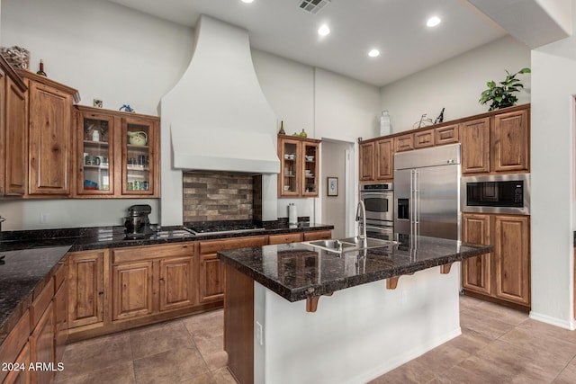 kitchen with a center island, a high ceiling, premium range hood, built in appliances, and a breakfast bar area