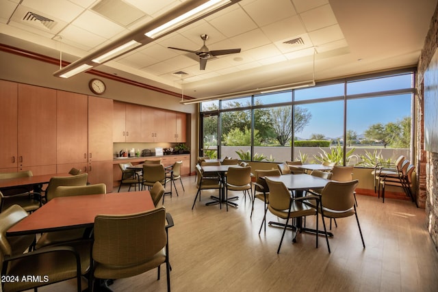 dining area featuring ceiling fan, a raised ceiling, a wealth of natural light, and light hardwood / wood-style flooring