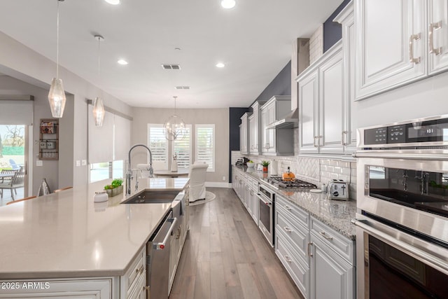kitchen featuring white cabinetry, stainless steel appliances, visible vents, decorative backsplash, and an inviting chandelier
