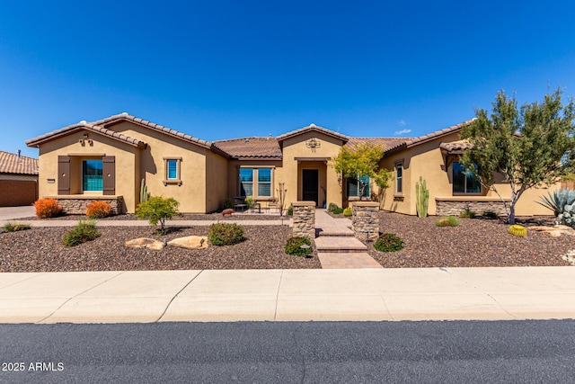 mediterranean / spanish-style house with stucco siding, a tiled roof, and stone siding