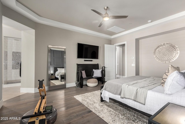 bedroom with a tray ceiling, baseboards, dark wood-style floors, connected bathroom, and ceiling fan