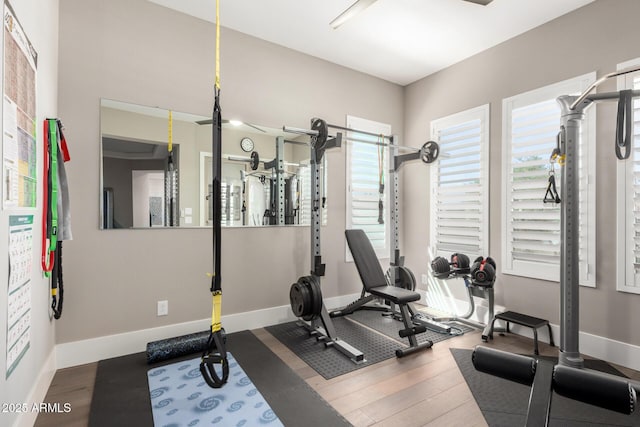 exercise room featuring baseboards, wood finished floors, and a healthy amount of sunlight
