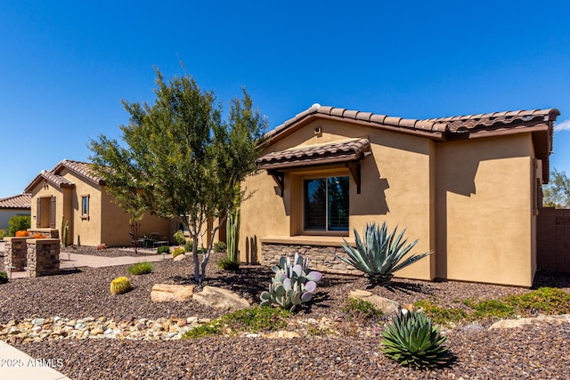 mediterranean / spanish-style house featuring stone siding, a tile roof, and stucco siding