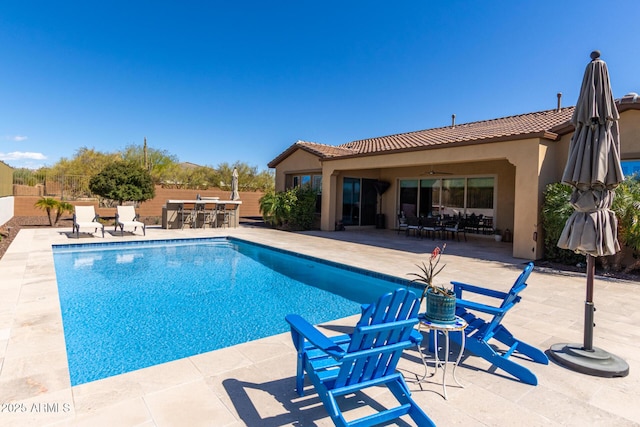 view of pool featuring a patio, fence, ceiling fan, and outdoor dry bar