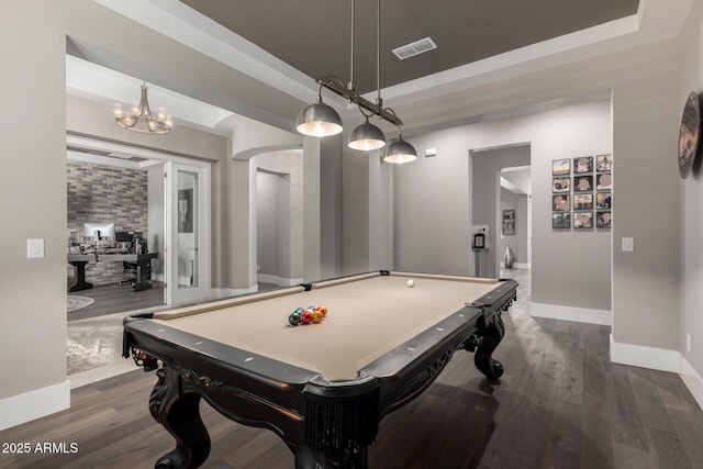 recreation room featuring a tray ceiling, baseboards, visible vents, and dark wood finished floors
