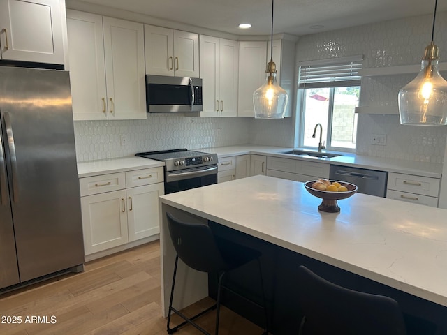 7802 E Hubbell St, Scottsdale, AZ 85257 - kitchen featuring appliances with stainless steel finishes, a sink, light wood-type flooring, a kitchen bar, and white cabinets