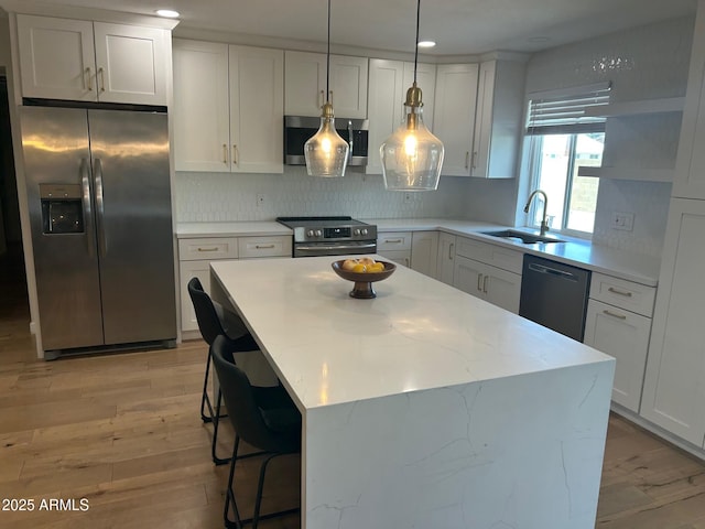 7802 E Hubbell St, Scottsdale, AZ 85257 - kitchen featuring stainless steel appliances, a sink, decorative backsplash, a kitchen island, and decorative light fixtures