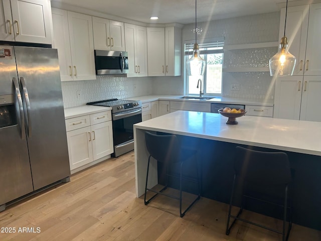 7802 E Hubbell St, Scottsdale, AZ 85257 - kitchen featuring appliances with stainless steel finishes, a breakfast bar area, light wood-style flooring, light countertops, and a sink