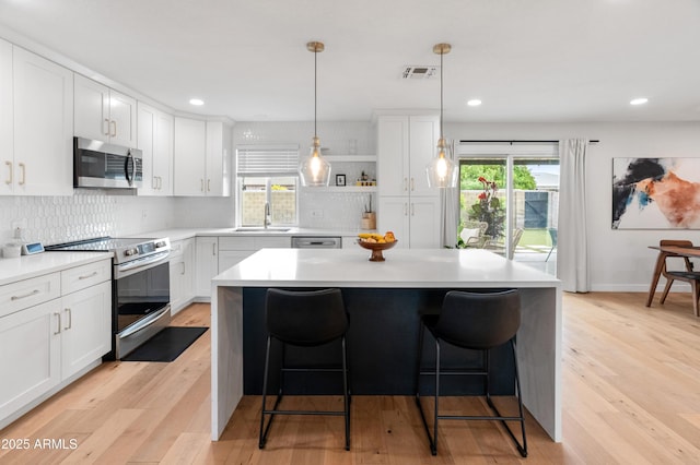 7802 E Hubbell St, Scottsdale, AZ 85257 - kitchen featuring appliances with stainless steel finishes, a sink, light wood finished floors, a kitchen bar, and light countertops