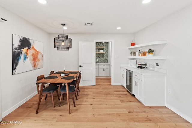 7802 E Hubbell St, Scottsdale, AZ 85257 - dining room with beverage cooler, a bar, light wood-type flooring, recessed lighting, and baseboards