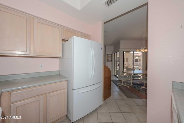 kitchen with a chandelier, light brown cabinets, white fridge, and light tile floors