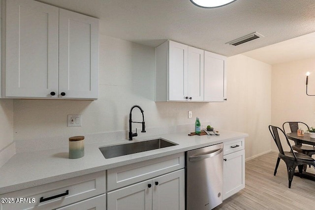 4268 N 68th Ave, Phoenix, AZ 85033 - kitchen with dishwasher, light countertops, light wood finished floors, and white cabinetry