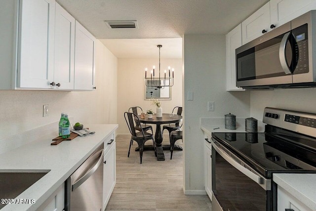 4268 N 68th Ave, Phoenix, AZ 85033 - kitchen featuring stainless steel appliances, a chandelier, white cabinetry, light countertops, and light wood-type flooring