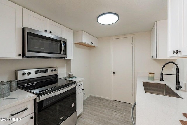 4268 N 68th Ave, Phoenix, AZ 85033 - kitchen with appliances with stainless steel finishes, white cabinets, light wood-style floors, and light stone countertops