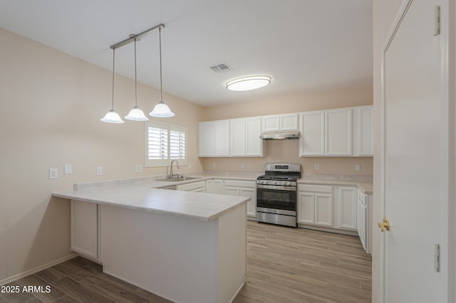 kitchen featuring visible vents, a peninsula, light countertops, stainless steel range with gas cooktop, and white cabinetry