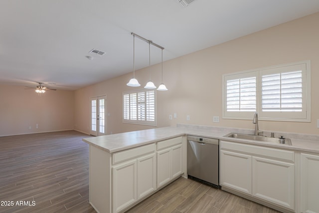 kitchen featuring a peninsula, a sink, visible vents, open floor plan, and stainless steel dishwasher